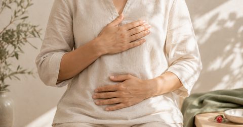 Frau legt beide Hände auf den Bauch