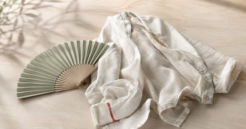 Zusammengelegter Fächer neben einer weißen Bluse